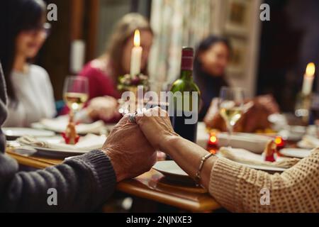 First we pray then we feast. Closeup shot of people holding hands in prayer before having a meal together. Stock Photo