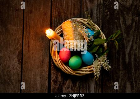 Easter dinner, colored chicken eggs and candle flame on an old wooden table in the evening Stock Photo