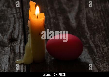 Easter dinner, colored chicken eggs and candle flame on an old wooden table in the evening Stock Photo