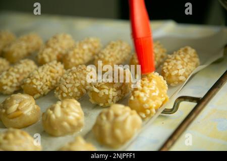 Penellets. Small sweets of various shapes, made from almond and potato dough, and covered with almonds or pine nuts. Stock Photo