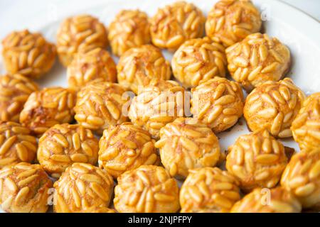 Penellets. Small sweets of various shapes, made from almond and potato dough, and covered with almonds or pine nuts. Stock Photo