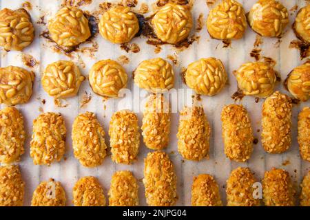 Penellets. Small sweets of various shapes, made from almond and potato dough, and covered with almonds or pine nuts. Stock Photo