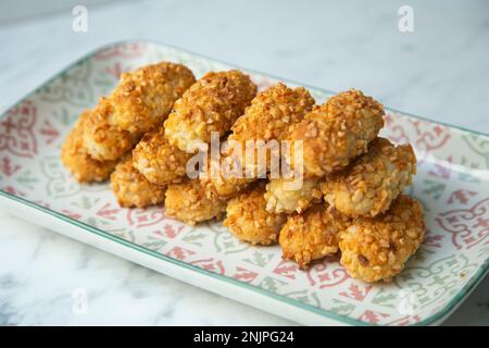 Penellets. Small sweets of various shapes, made from almond and potato dough, and covered with almonds or pine nuts. Stock Photo