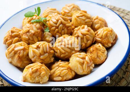 Penellets. Small sweets of various shapes, made from almond and potato dough, and covered with almonds or pine nuts. Stock Photo