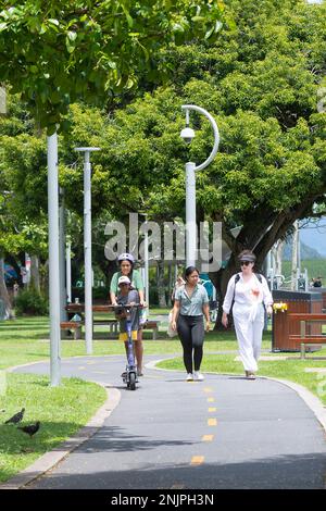 People walking and on e-scooter on Promenade Path, Cairns Esplanade, Far North Queensland, FNQ, QLD, Australia Stock Photo