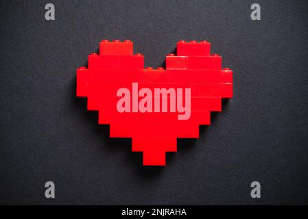 Red heart made of plastic bricks on a dark gray background Stock Photo