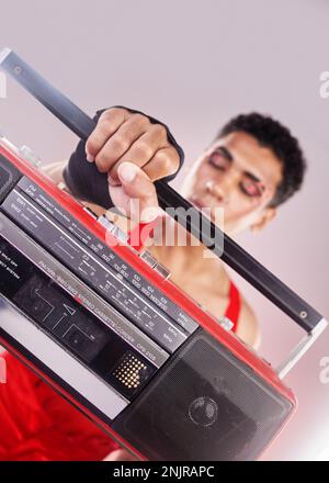 Closeup, retro radio and black man with music, makeup and fashion against grey studio background. Zoom, boom box and cassette player with queer male Stock Photo