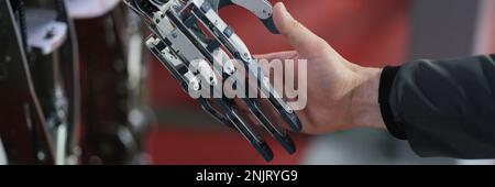 Robot extends its hand to man for handshake Stock Photo
