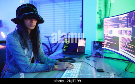 Programming, software and data with a black woman developer working in a neon office for information technology. Computer, cyber security and database Stock Photo