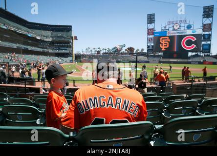 Wearing a Madison Bumgarner jersey, Adam Serrano and his son Christian, 5  1/2, settle into their seats for the Giants game against the Chicago Cubs  at Oracle Park in San Francisco, Calif.