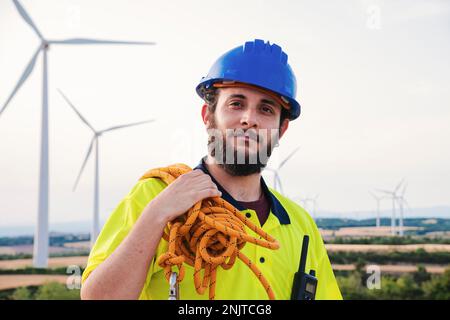 Technician or engineer of wind mill turbine and renewable energy professional standing looking at camera wearing a helmet and security wear. Sustainable power concept. High quality photo Stock Photo
