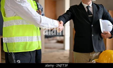 Caucasian businessman in formal business suit is shaking hands with an engineer manager while inspecting the construction site. cropped image Stock Photo