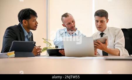 Two professional Caucasian businessmen in the meeting with an Asian businessman, discussing and cooperating work. Diverse people concept Stock Photo