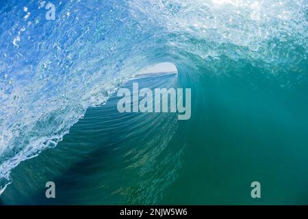Wave  ocean swimming inside hollow tubing blue water a surfer surfing ride view closeup water photography. Stock Photo