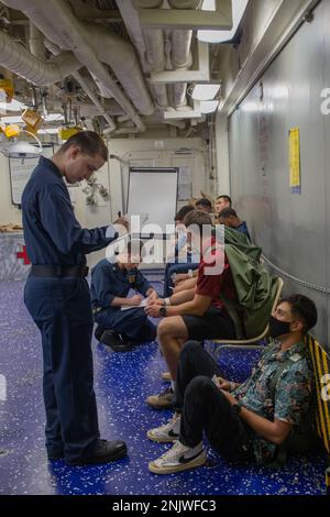 U.S. Navy Sailors conduct medical checks on simulated American citizens during a non-combatant evacuation operation training aboard the Amphibious Assault Ship USS Tripoli (LHA-7) in the Philippine Sea, Aug. 10, 2022. NEO training ensures the Tripoli Amphibious Ready Group is ready to receive American citizens if they need to be evacuated from a foreign country. The 31st MEU is operating aboard ships of the Tripoli ARG in the 7th Fleet area of operations to enhance interoperability with allies and partners and serve as a ready response force to defend peace and stability in the Indo-Pacific re Stock Photo