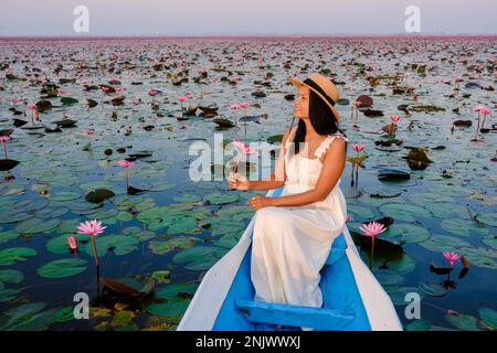 Asian women in a boat at the Beautiful Red Lotus Sea full of pink flowers in Udon Thani in northern Thailand. Flora of Southeast Asia.  Stock Photo