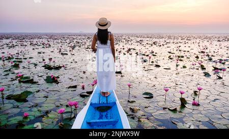 Asian women in a boat at the Beautiful Red Lotus Sea full of pink flowers in Udon Thani in northern Thailand. Flora of Southeast Asia.  Stock Photo