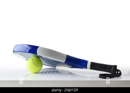 Padel racket and ball reflected on white table and white isolated ...