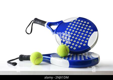 Set of paddle tennis rackets and balls the reflected on white table and white isolated background. Front view. Stock Photo