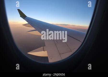 This breathtaking stock photo captures the view from a passenger airplane window, showcasing a majestic wing soaring through the clear, cloudless sky Stock Photo