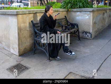 London, England, UK. Young Japanese woman on her mobile phone Stock Photo