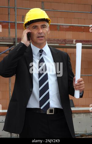 architect talking on the phone on the construction site, front view Stock Photo