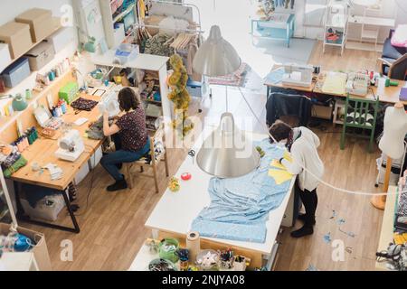 High angle of female tailors working with fabric together while creating creative patterns in workshop Stock Photo