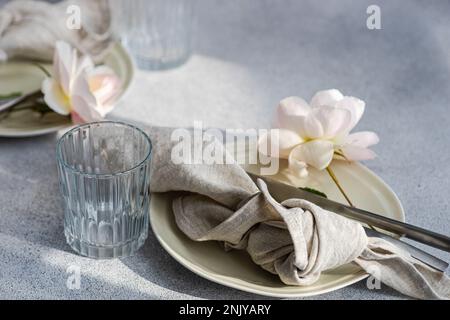Table setting with white ceramic plates and white blooming roses Stock Photo
