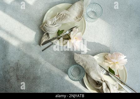 Table setting with white ceramic plates and white blooming roses Stock Photo