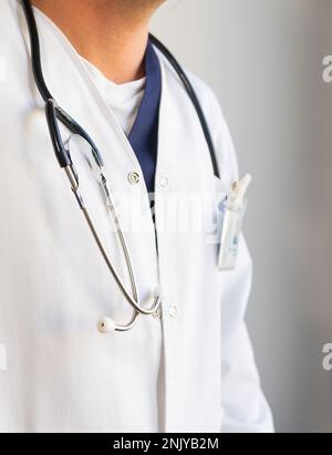 Anonymous male doctor in white uniform with stethoscope on neck standing in light clinic Stock Photo
