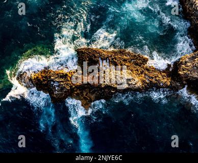 Top aerial view of powerful stormy sea waves splashing on rocky cliff on summer day in Ciutadella de Menorca Stock Photo