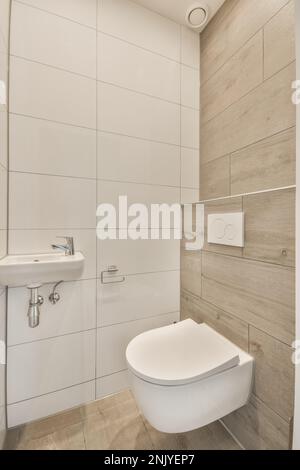 White sink and wall mounted toilet small bathroom with white and beige tiles at home Stock Photo