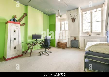 Interior design of bedroom with comfortable bed placed near windows against bright wall and desk with chair in modern apartment Stock Photo