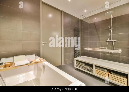 Interior of contemporary bathroom with white ceramic bathtub and towels on shelves in modern apartment Stock Photo
