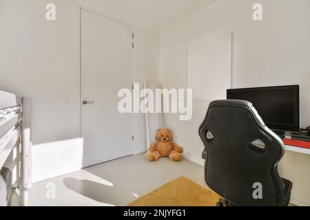 Interior design of modern room with comfortable furniture and computer monitor placed on table with teddy bear in corner Stock Photo