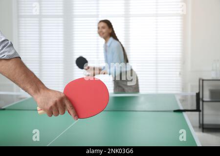 Business people playing ping pong in office, focus on tennis racket Stock Photo