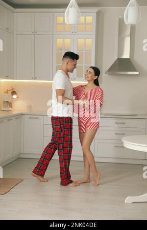 Happy couple wearing pyjamas and dancing in kitchen Stock Photo