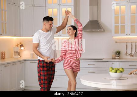 Happy couple wearing pyjamas and dancing in kitchen Stock Photo