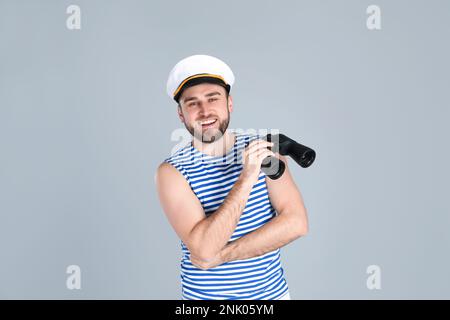 Happy sailor with binoculars on light blue background Stock Photo - Alamy