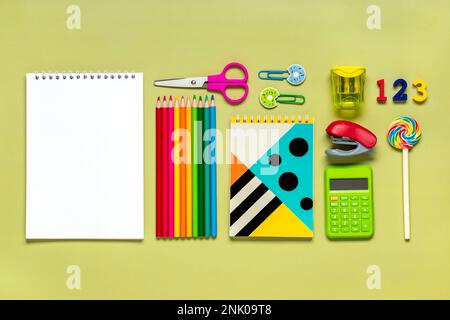 Frame from school and office supplies Paper clips, pens, calculator, sharpener, notepad, stapler isolated on green background Flat lay Top view Back t Stock Photo