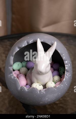 photo of a rabbit sitting in an egg with small eggs inside on a glass table Stock Photo