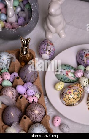 photo painted in different colors eggs and ceramic rabbit on the table Stock Photo