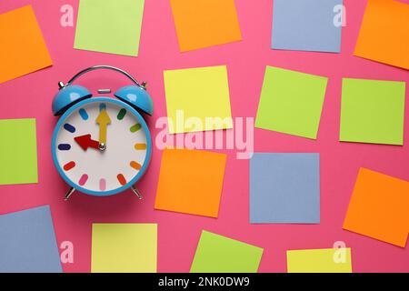 Alarm clock and blank reminder notes on pink background, flat lay Stock Photo