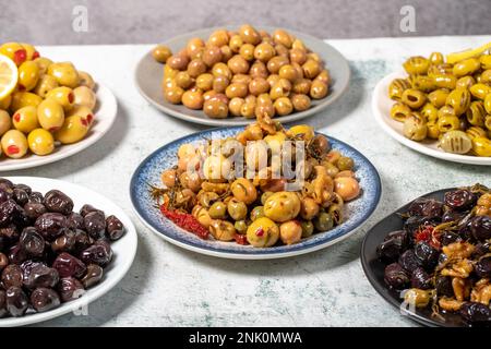 Olive varieties. Assortment of black and green olives on plate on gray background Stock Photo