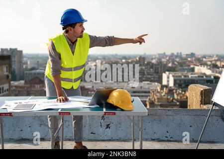 Young businessman construction site engineer working with architect blueprints on construction site. Stock Photo