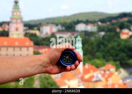 Tourist holds compass against medieval town Cesky Krumlov in Czech Republic. Travel, vacation and hiking. Summer, spring holidays, recreation for peop Stock Photo