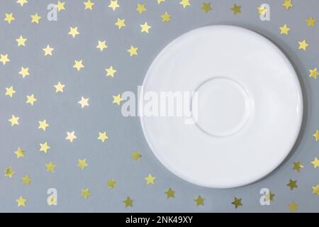 Empty plate saucer on a gray background with stars. Concept Christmas and New Year, holiday. Copy space Stock Photo
