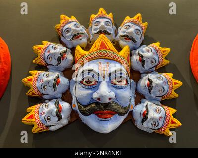 Handmade colorful tribal look of Ravan face mask souvenir hanging on plain black background. Selective focus on object. Stock Photo