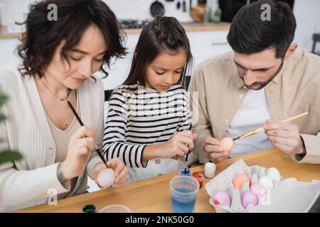 parents and child painting Easter eggs in kitchen Stock Photo