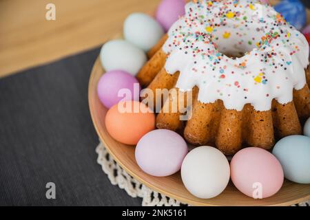 High angle view of sweet Easter cake and painted pastel colors eggs on table at home Stock Photo